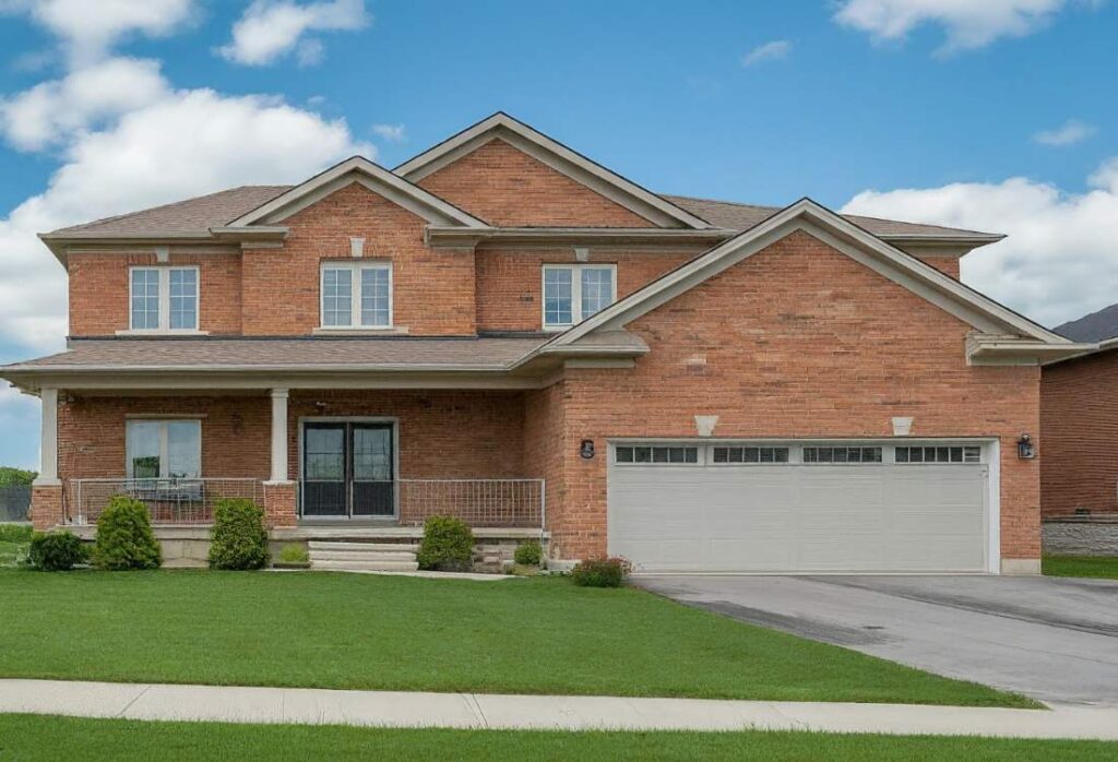 Selling a home in Stittsville. A beautiful detached suburban home in Stittsville, Ontario with a two-car garage attached. The house has a classic design and a well-maintained lawn. A bright blue sky with fluffy white clouds completes the picture.