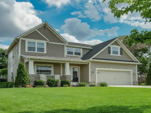 Stittsville Home, a two-story house stands tall against the backdrop of a clear sky. Its exterior showcases earthy brown bricks, lending a classic charm to the structure.