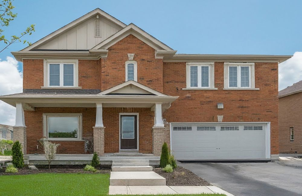 Selling Your Home in Kanata Lakes. A 2-storey red brick house with a driveway and 2 car garage.