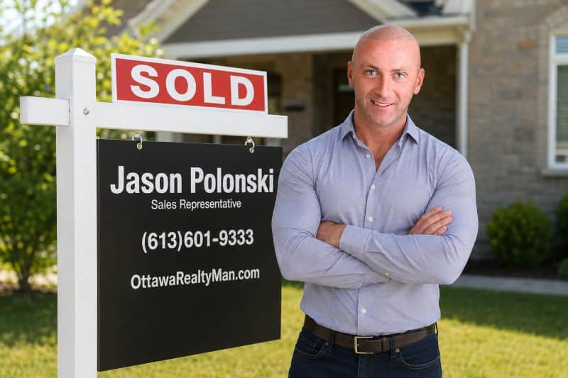 Jason Polonski- Realtor in Kanata, Ottawa is standing next to his sold sign wearing a blue shirt